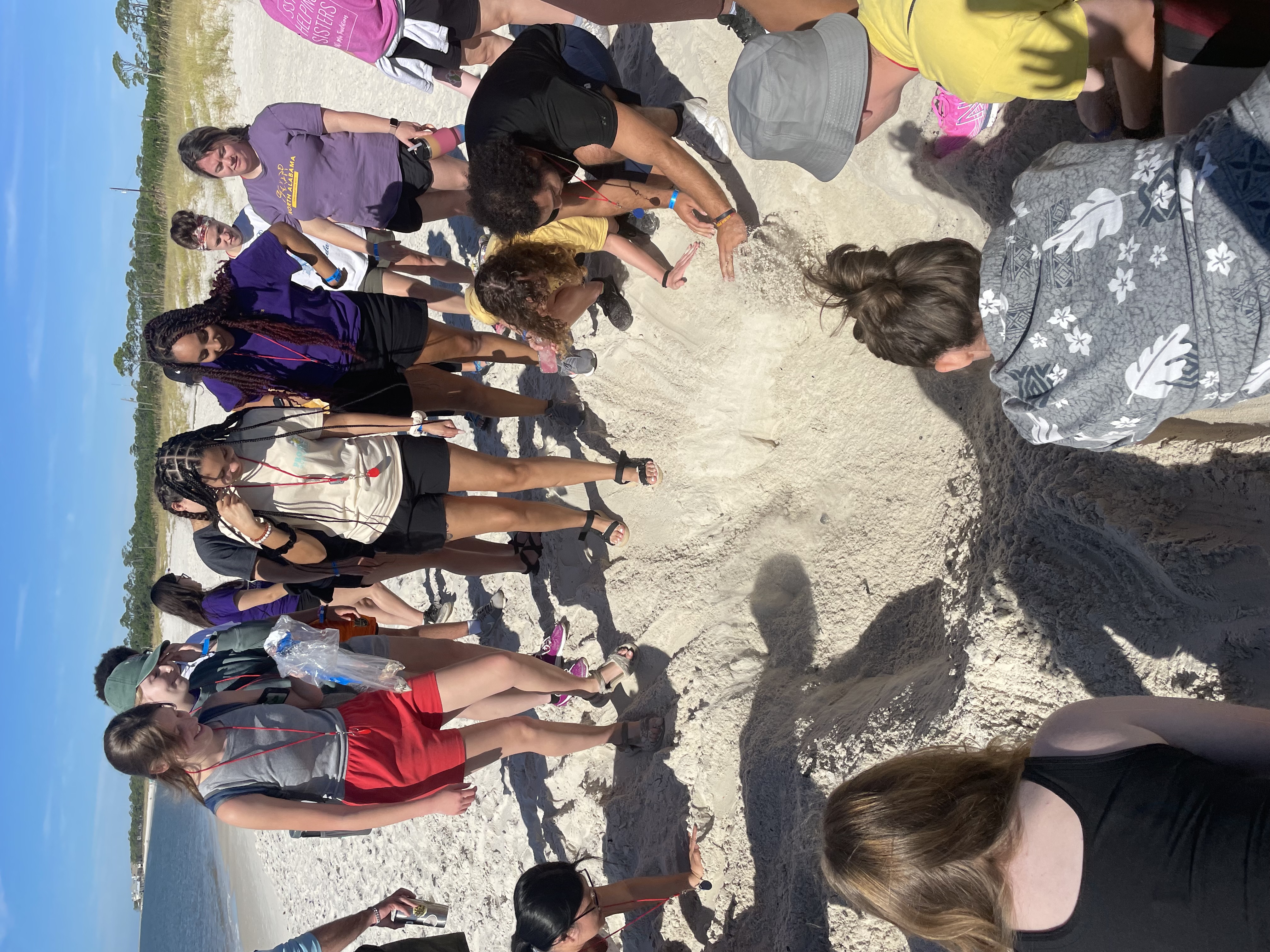 Students gathered around a small hole in the sand