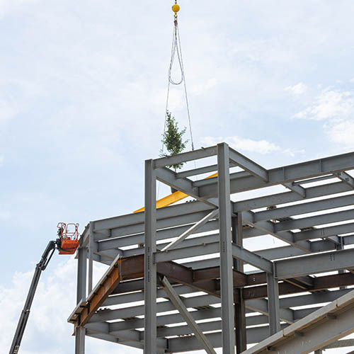 crane lifting beam on construction site with signatures and tree