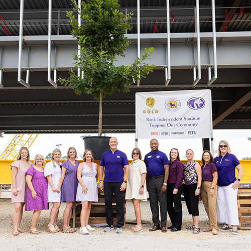 donor group standing in front of signature beam